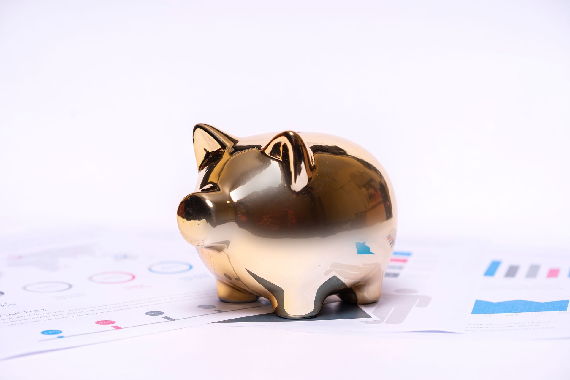 Close-up of a golden piggy bank on financial documents, symbolizing savings and investment.